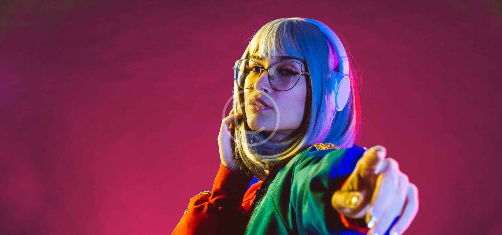 Mujer con lentes y auriculares señalando a la camara